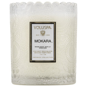 A coconut wax candle in a glass with scalloped edging mokara fragrance voluspa